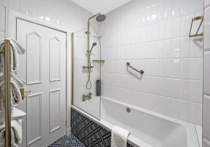 La salle de bains blanche est pourvue d'une baignoire et d'une douche. dans l'établissement The Atholl Palace, à Pitlochry