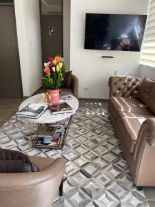 a living room with a couch and a table with flowers at Apart-hotel Villakayro in Moquegua