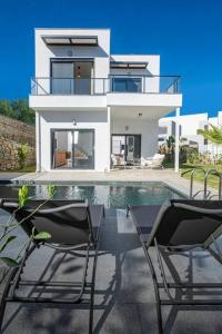 a white house with a swimming pool and two chairs at Villa Al Mare 2; Koyunbaba'da Özel Havuzlu Villa in Bodrum City