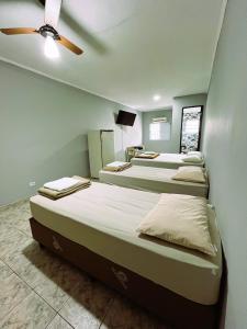 three beds in a room with a ceiling fan at Pousada Aviação in Praia Grande