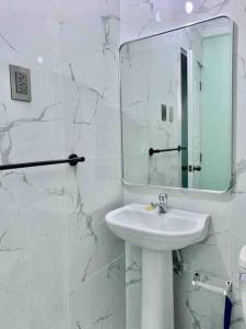 La salle de bains blanche est pourvue d'un lavabo et d'un miroir. dans l'établissement Apartaestudio Doña Rosa, à San Pedro de Macorís