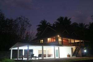 une maison éclairée la nuit avec une terrasse dans l'établissement Bann Mangkud Khaolak, à Khao Lak