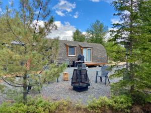 a tiny house in the woods with a table and chairs at Le POD'Stress / Nature et tranquilité in Saint-Alexis-des-Monts