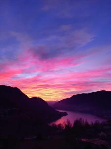 una puesta de sol sobre un cuerpo de agua con montañas en B&B Le Magnolie, en Faggeto Lario 