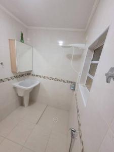 a white bathroom with a sink and a shower at Apto completo - Solemar/PG in Praia Grande