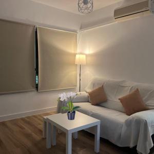 Una sala de estar con un sofá blanco y una mesa. en Piso cercano al recinto ferial, en Jerez de la Frontera