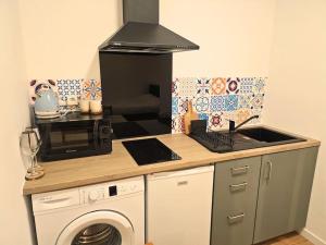 een keuken met een fornuis oven naast een wasmachine bij NERO studio confort tt équipé! in Villejuif