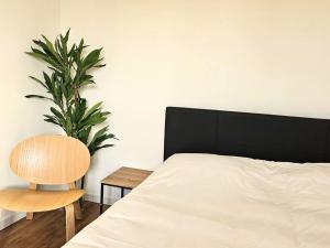 een slaapkamer met een bed en een stoel en een plant bij NERO studio confort tt équipé! in Villejuif