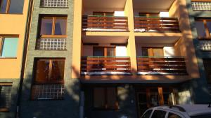 apartamentowiec z balkonami i samochód zaparkowany przed budynkiem w obiekcie Apartmán Tatry Tatranská Štrba w mieście Tatranska Strba