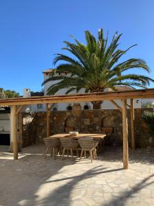a wooden pergola with a table and chairs and a palm tree at Casa Lila Javea in Jávea
