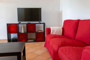 a living room with a red couch and a flat screen tv at Chalet Font de Sa Cala in Font de Sa Cala