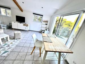 a living room with a table and chairs and a television at Parenthèse du Pic Appartement Climatisé 1 à 6p MEUBLE DE TOURISME 2 ETOILES in Saint-Martin-de-Londres
