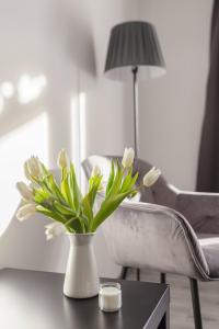 un jarrón con flores blancas sobre una mesa con una silla en Deluxe Apartments 55, en Rateče