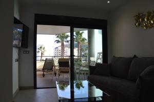 uma sala de estar com um sofá e uma mesa de vidro em Albir Beach & Sea Apt em Albir