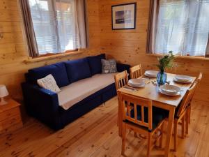 a living room with a blue couch and a table at Domek z Bala Pod Żaglami in Pobierowo