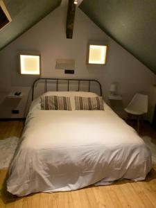 a bedroom with a white bed with two windows at Froissart Loft in Chimay