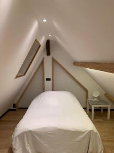 una camera da letto con letto bianco in mansarda di Froissart Loft a Chimay