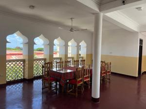 a dining room with a table and chairs and windows at Bin Omiar Malindi Apartment in Stone Town +12 photos