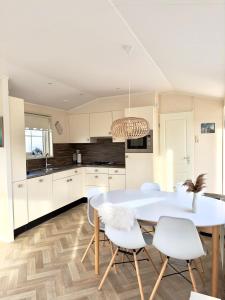 a kitchen with a white table and white chairs at Chalet Sirun Strandcamping Valkenisse, Biggekerke in Biggekerke