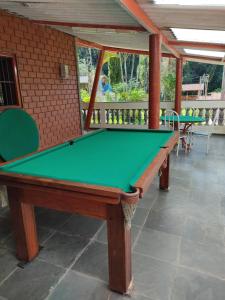 Chácara, 3 suítes, piscina, lago, wi-fi 250 mbps في جوارولوس: طاولة بلياردو خضراء في غرفة مع طاولتين