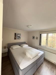 1 dormitorio con 1 cama con sábanas blancas y ventana en Chalet Sirun Strandcamping Valkenisse, Biggekerke en Biggekerke