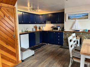 een keuken met blauwe kasten en een tafel en stoelen bij Hideaway Cottage in Schull