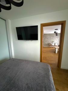 a bedroom with a flat screen tv on the wall at Jurajska Plaza - Nowoczesny apartament z osobną sypialnią, Parking GRATIS - HK Apartaments Kielce in Kielce