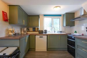 a kitchen with green cabinets and a sink at Orchard Bungalow - Sleeps 10 - Close to Town Centre - Free Parking, PlayStation, Fast Wi-Fi and Smart TV with Netflix by Yoko Property in Northampton