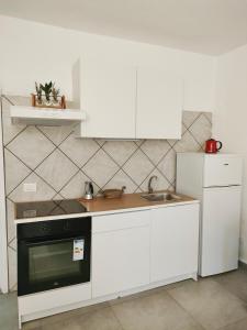 a kitchen with white cabinets and a sink and a refrigerator at Casa Il Fabbro in Il Fabbro