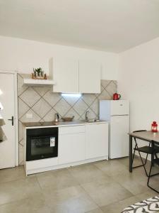 La cuisine est équipée de placards blancs, d'un réfrigérateur et d'une table. dans l'établissement Casa Il Fabbro, à Il Fabbro