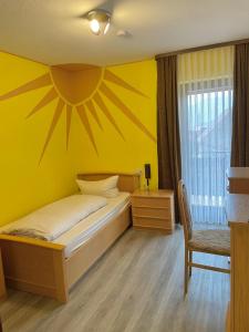 a yellow bedroom with a bed and a window at Gasthof Rhönlust in Bischofsheim an der Rhön
