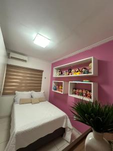 a bedroom with a bed and a pink wall at Quarto em casa de condominio fechado in Santarém