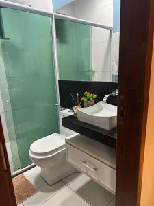 y baño con aseo, lavabo y espejo. en Quarto em casa de condominio fechado, en Santarém