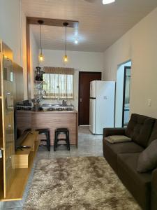 a living room with a couch and a kitchen with a refrigerator at Apart Aconchego Mobiliado Centro in Sinop
