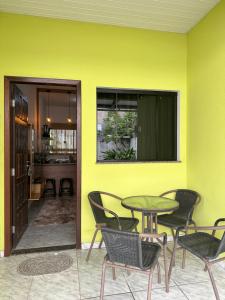 a yellow wall with a table and chairs at Apart Aconchego Mobiliado até 4 pessoas Centro in Sinop