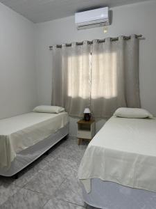 1 dormitorio con 2 camas y ventana en Apart Aconchego Mobiliado até 4 pessoas Centro en Sinop