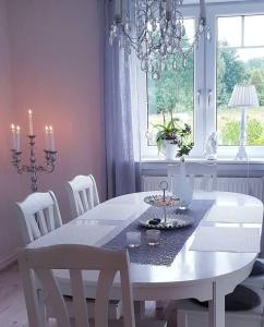 a white dining room table with chairs and a chandelier at Höhällets Lantliga Rum in Värnamo