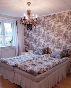 a large bed in a bedroom with a chandelier at Höhällets Lantliga Rum in Värnamo