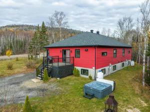 an aerial view of a red house with a yard at Chalet des Érables-3 bedrooms, jacuzzi & relax in Petite-Rivière-Saint-François