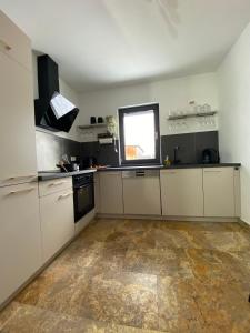 a large kitchen with white cabinets and a window at FeWo Max Nähe HUK, neu eingerichtet und renoviert in Coburg