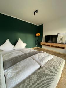 una camera da letto con un grande letto con una parete verde di FeWo Max Nähe HUK, neu eingerichtet und renoviert a Coburg