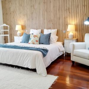 a bedroom with a large bed and a white chair at Casa by Anita Guesthouse in Esposende