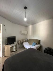 1 dormitorio con 1 cama, TV y sofá en Casa com suíte, en Blumenau
