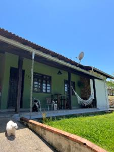a green house with a cat sitting outside of it at Casa com suíte in Blumenau