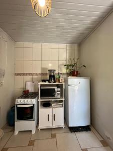 a small kitchen with a refrigerator and a microwave at Casa com suíte in Blumenau