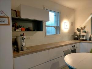 cocina con armarios blancos, mesa y ventana en Chez Nadège et Nicolas, en Aubergenville