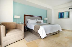 a bedroom with a large bed and a chair at HB Xalapa in Xalapa