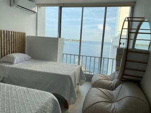 een slaapkamer met 2 bedden en uitzicht op de oceaan bij Apartamento con hermosa vista al mar, Cristoforo en el Laguito Cartagena a pocos pasos de la playa in Cartagena