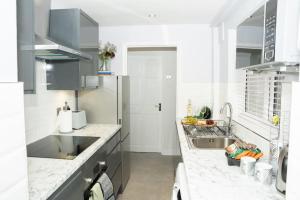 a white kitchen with a sink and a refrigerator at Stylish home in York - Free Wifi & Parking - Close to Racecourse & City Centre in York