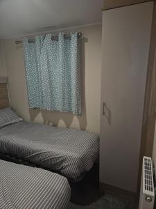 een slaapkamer met 2 bedden en een douchegordijn bij Jenny,s place in Saint Osyth